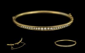 Victorian Period 9ct Gold Seed Pearl Set Hinged Bangle with safety chain, not marked but tests as