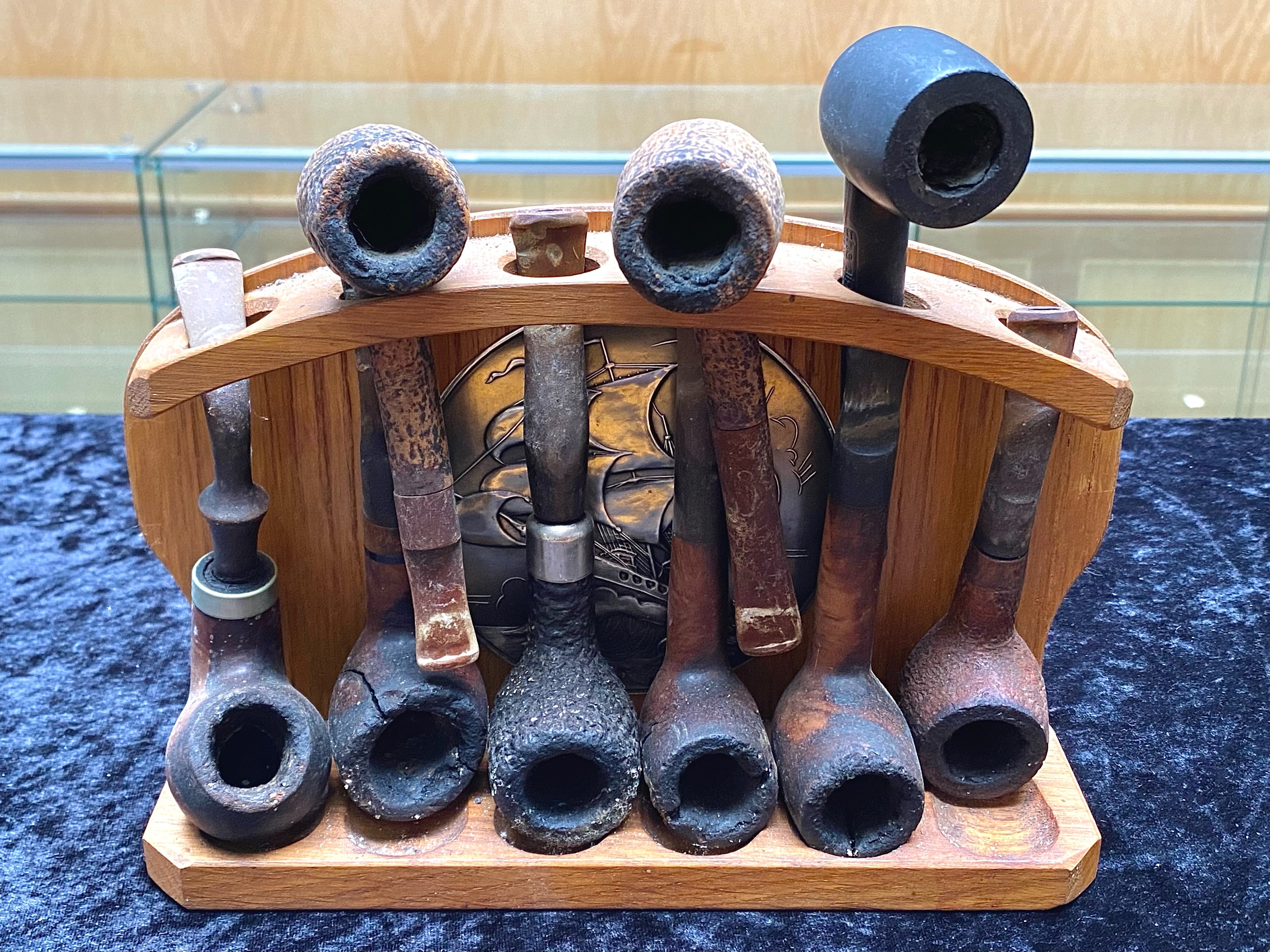Collection of Clay Pipes, in a fitted wooden display case decorated with a central metal circular