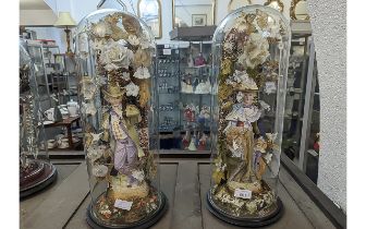 Pair of Victorian Bisque Figures inside glass domes, a traditional lady and gentleman surrounded