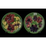Two Moorcroft Plates, 10'' diameter, one dark green with Hibiscus pattern, one dark green with