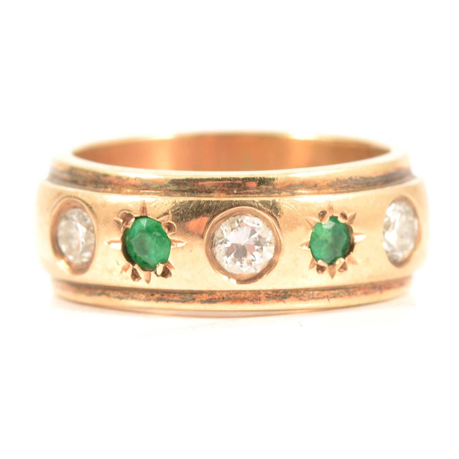 An emerald and diamond gypsy set ring.