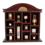 Collection of twelve miniature clocks in stained wood display stand