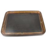A large black ebonised papier mache tray with gilded grape and vine border.