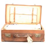 A large leather suitcase containing some fabrics.