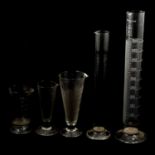 Collection of thermometers, glass measures and flasks, a cylindrical weighted wooden block, and othe