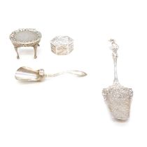 A silver miniature table, small white metal pill box, small slice and sugar scoop.