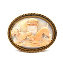 An oval carved shell cameo depicting a dog, cat and cockerel mounted in a strut frame.