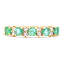 An emerald and diamond half eternity ring.