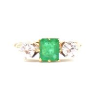 An emerald and diamond three stone ring.