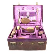A leather travelling vanity case with silver topped jars and brushes.