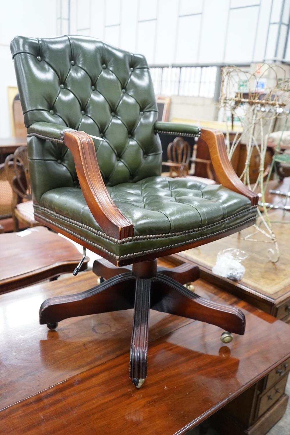 A reproduction mahogany and buttoned green leather swivel desk chair, width 56cm, depth 51cm, height