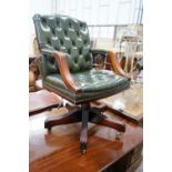 A reproduction mahogany and buttoned green leather swivel desk chair, width 56cm, depth 51cm, height