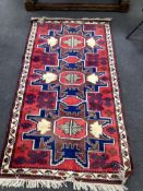 A Caucasian style red ground triple medallion rug, 180 x 98cm