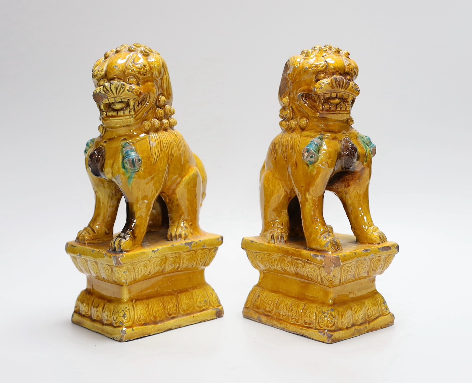 A pair of Chinese ochre glazed Buddhist lion figures, 25cm