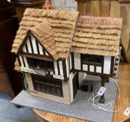 A contemporary doll's house modelled as a thatched house with accompanying furniture, width 70cm,