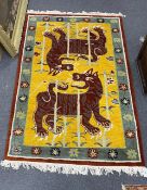 A Tibetan wool gold ground rug with twin tiger motif, 186 x 124cm