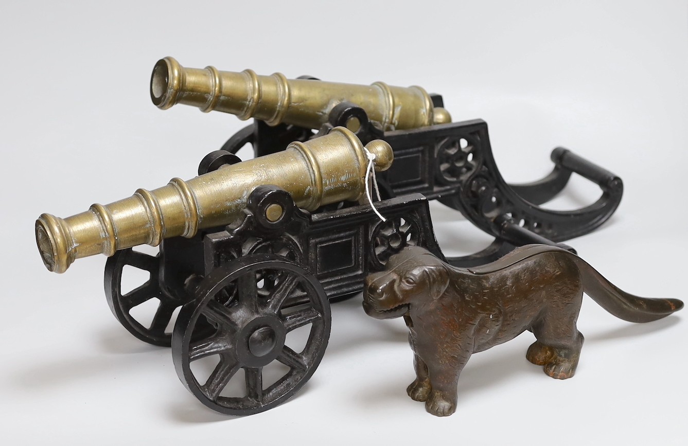 A pair of cast iron and bronze model cannons and a cast iron ‘dog’ nut cracker, cannons 42.5cm long