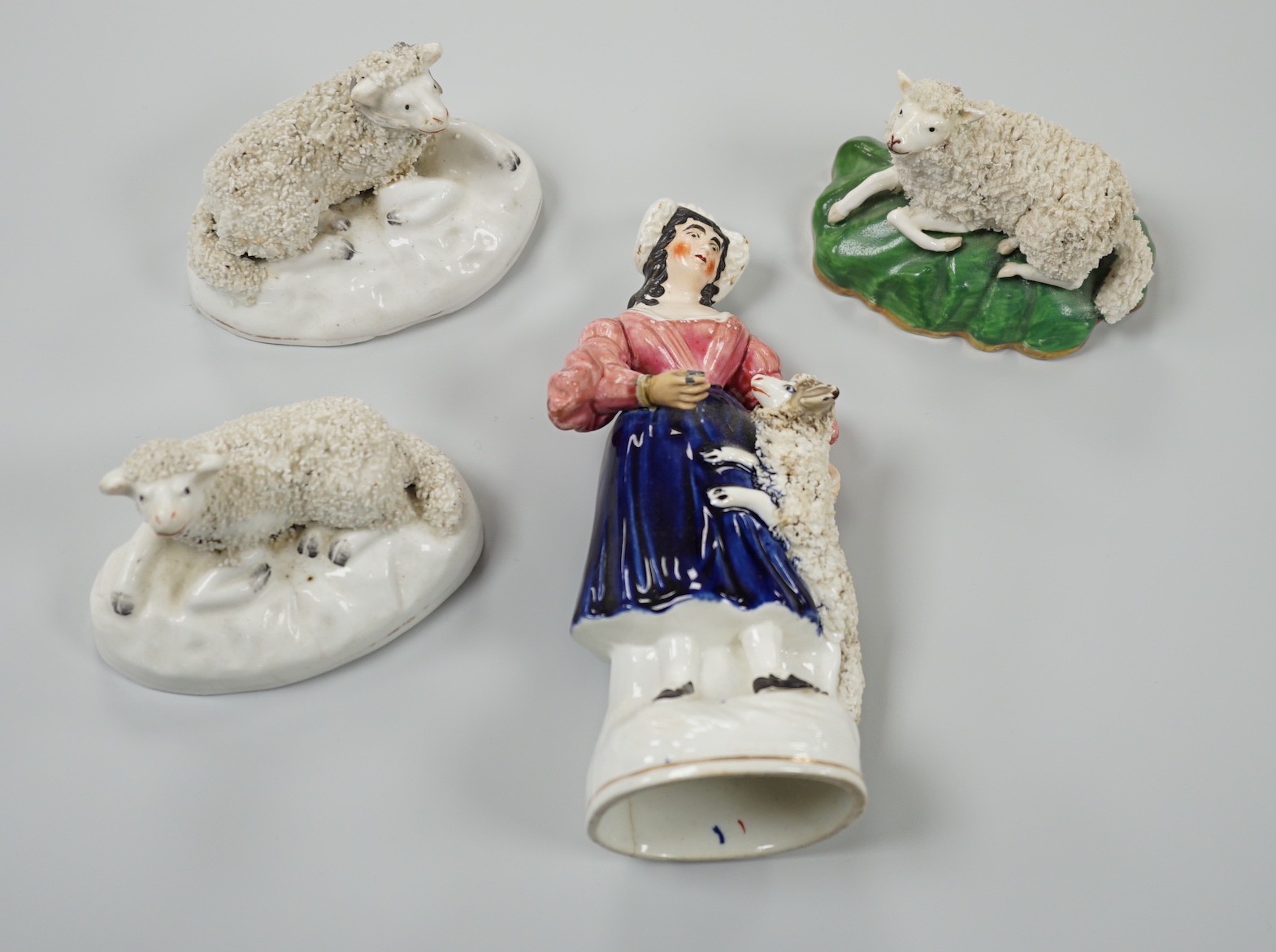 Three small Staffordshire models of recumbent sheep on oval mounted bases, together with a