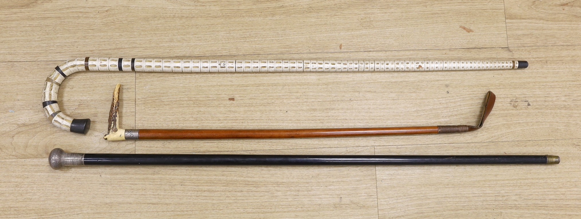 A silver mounted ebony walking cane, a shark vertebrae walking stick and a stag antler mounted