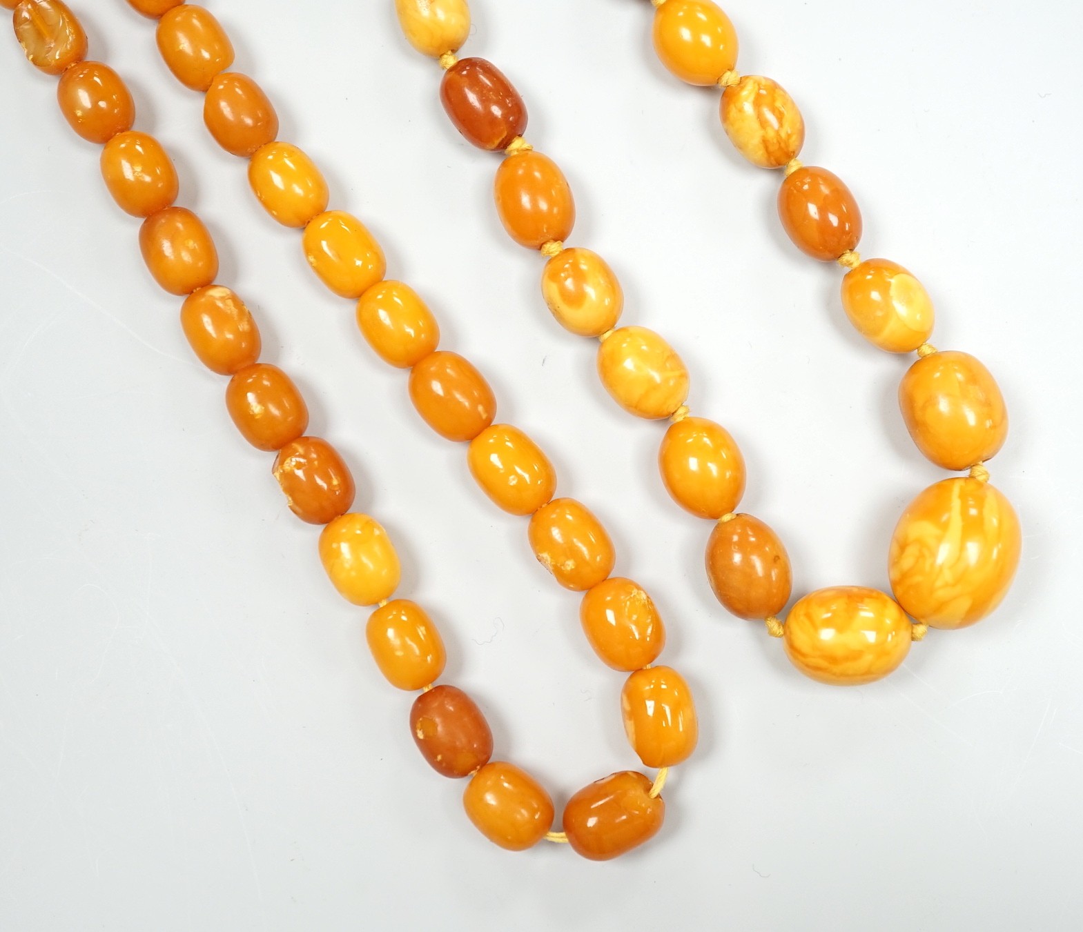 Two single strand graduated oval amber bead necklaces, one a.f., longest 43cm, gross weight 38