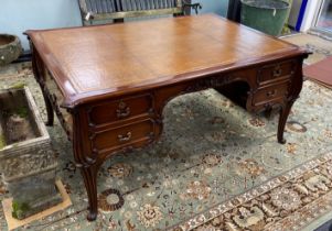 An early 20th century mahogany kneehole partner's desk with tooled tan leather inset top, length