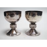 A stylish pair of Elizabeth II Arts & Crafts style planished silver pedestal cups, with