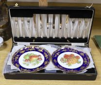 A cased dessert service containing six gilt and fruit decorated plates and a set of knives and