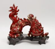 A Chinese red glazed figure of a dragon, on hardwood stand. 28cm wide