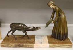 An Art Deco painted spelter model of a peasant girl feeding a deer with faux ivory mounts, the