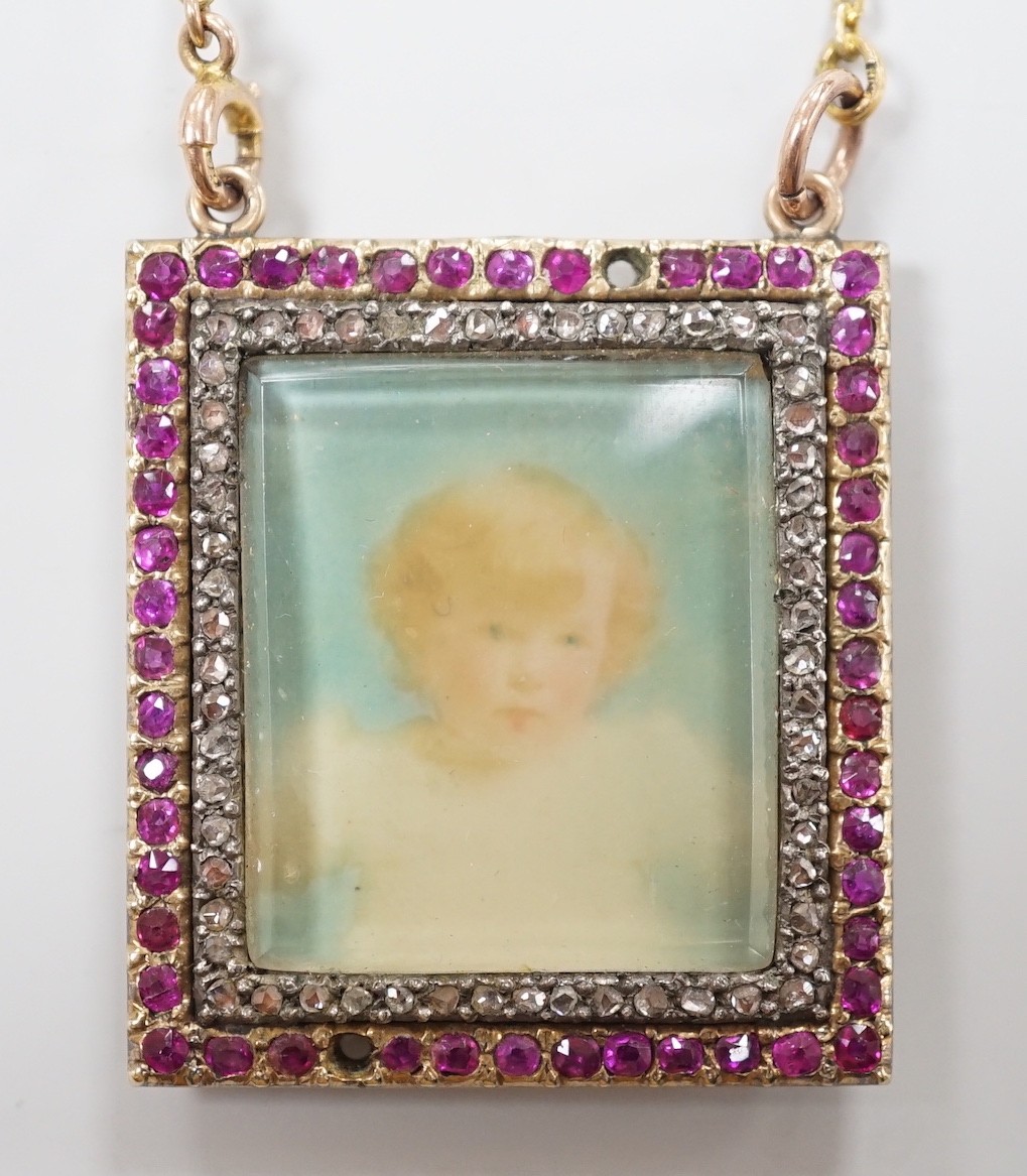 An early 20th century yellow metal, ruby and diamond mounted portrait pendant, 34mm (two rubies