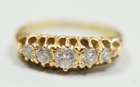 An early 20th century gold and graduated five stone diamond set half hoop ring, size O/P, gross