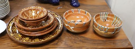 Four French pottery slip ware style pottery bowls and a pottery five similar dishes, largest 33cms