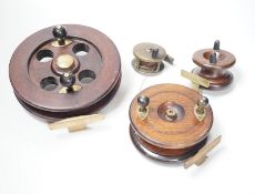 Three mahogany and brass fishing reels, largest 19 cm diameter and an Army & Navy brass reel, 6.