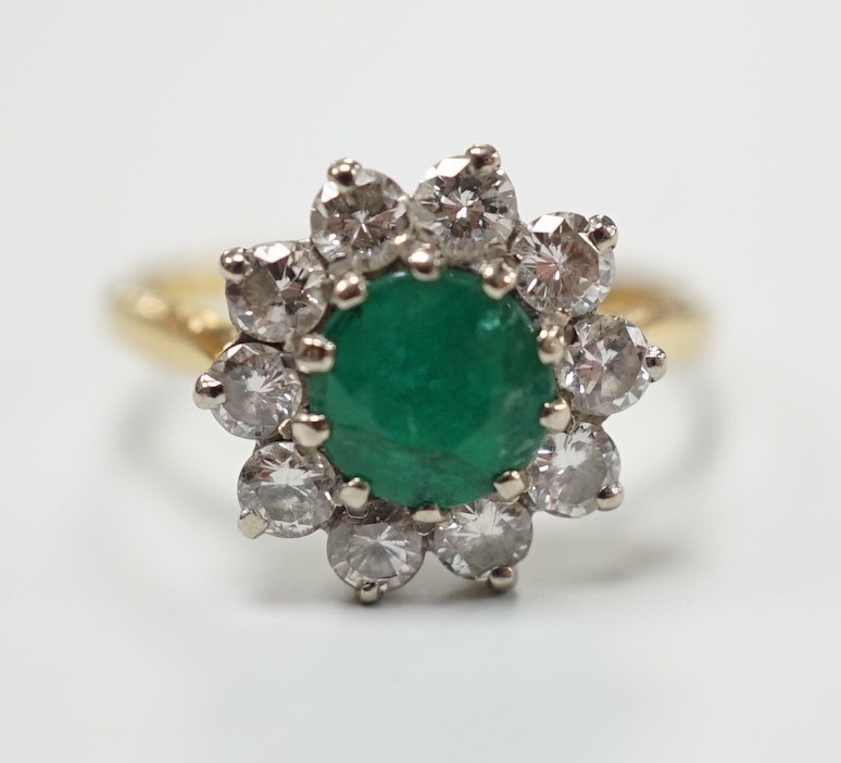 An 18ct, emerald and diamond set circular cluster ring, size K, gross weight 3 grams.