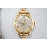 A lady's 750 yellow metal Universal manual wind wrist watch, on associated gold plated bracelet.