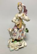 A Derby porcelain figure, modelled as a shepherdess playing a mandolin, seated on a stump, 18th