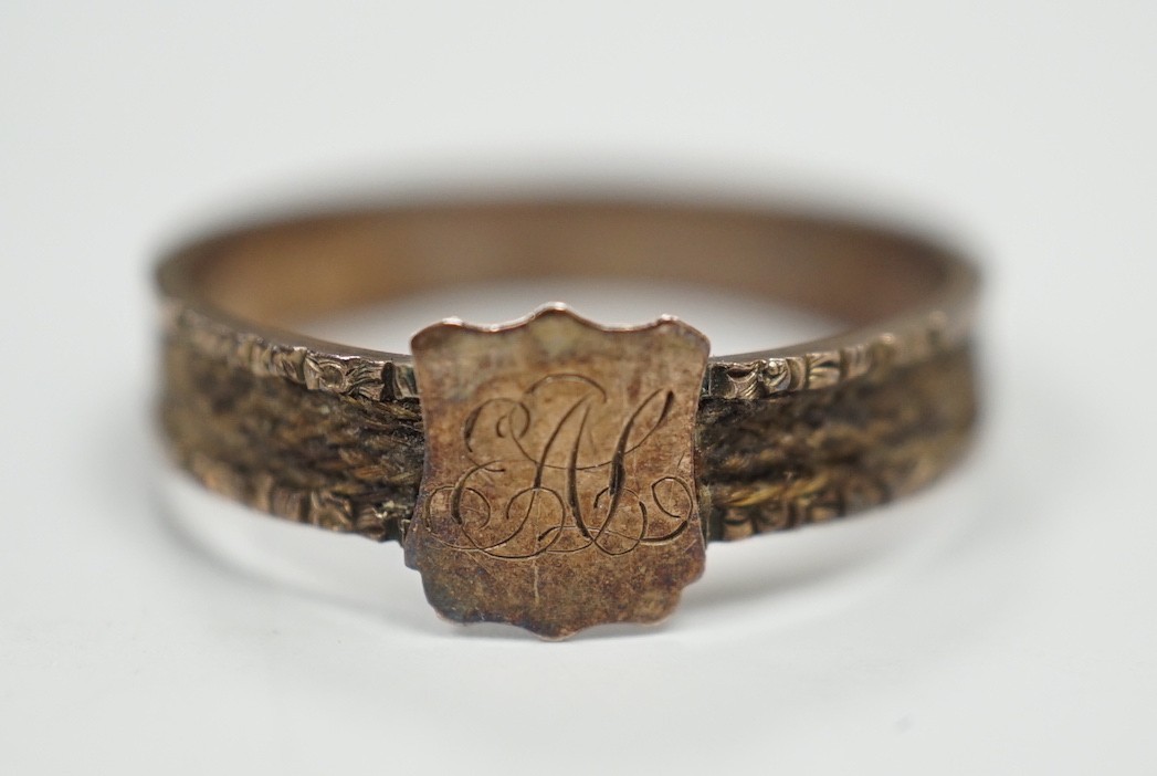 A Victorian yellow metal mourning ring, with engraved monogram and shank inset with plaited hair,