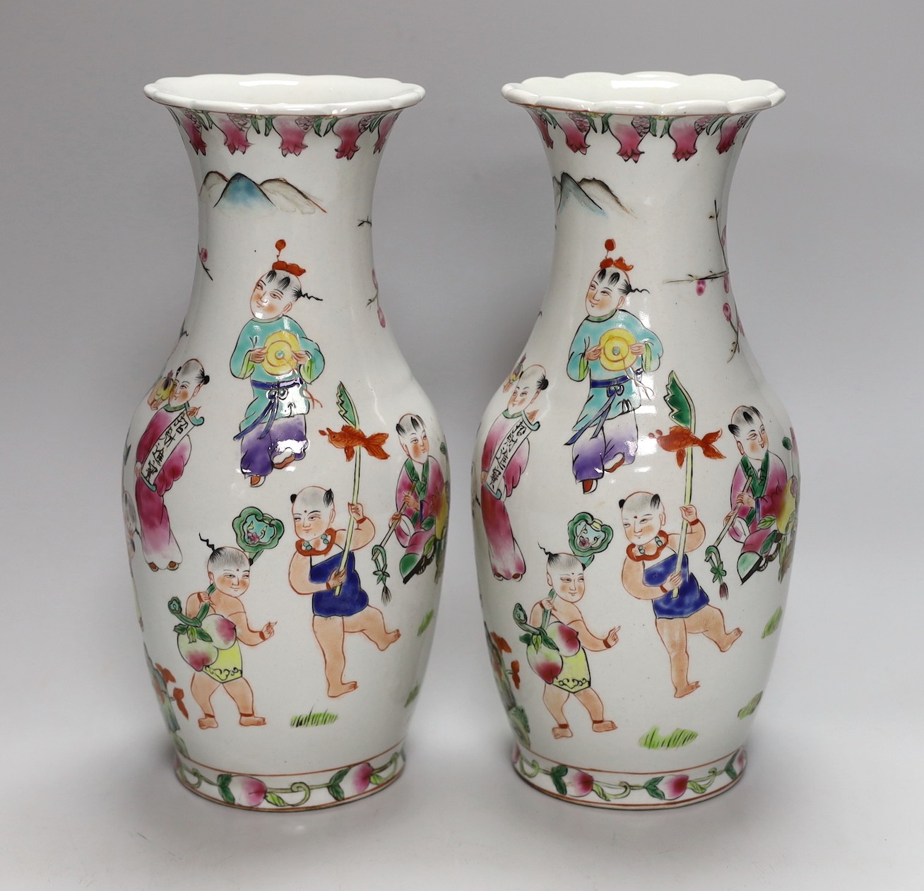 A pair of Chinese Famille Rose ‘boys’ vases, 25cms high