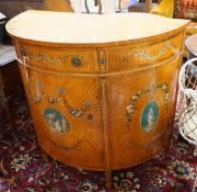 An Edwardian Sheraton revival painted satinwood demi lune side cabinet, width 107cm, depth 52cm,