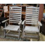 A pair of weathered teak folding garden armchairs, height 112cm