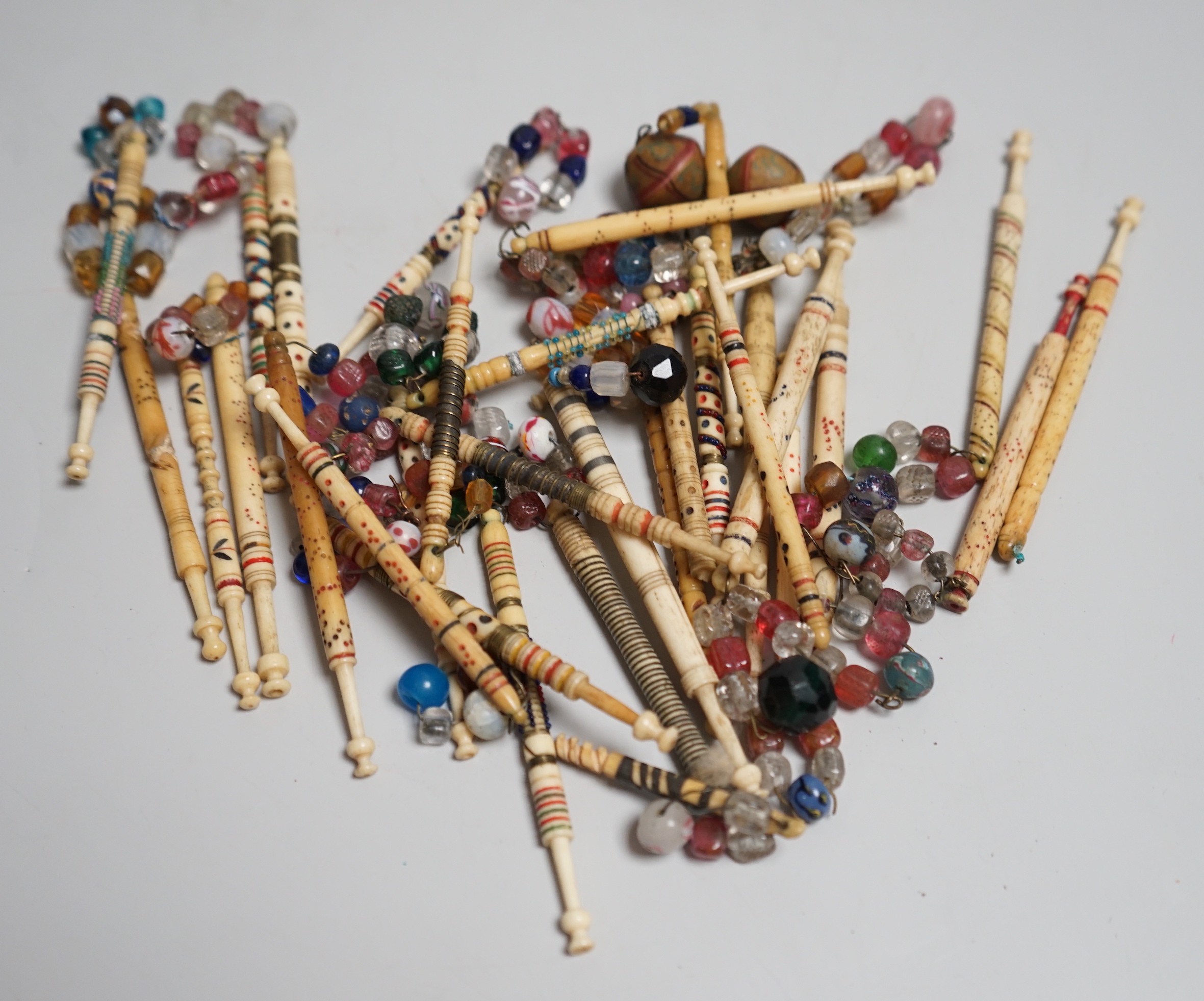 Twenty 19th century ornately decorated lace bobbins with glass bead tops and eleven carved bobbins