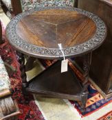A 1920's circular oak drop flap two tier occasional table, diameter 61cm, height 69cm