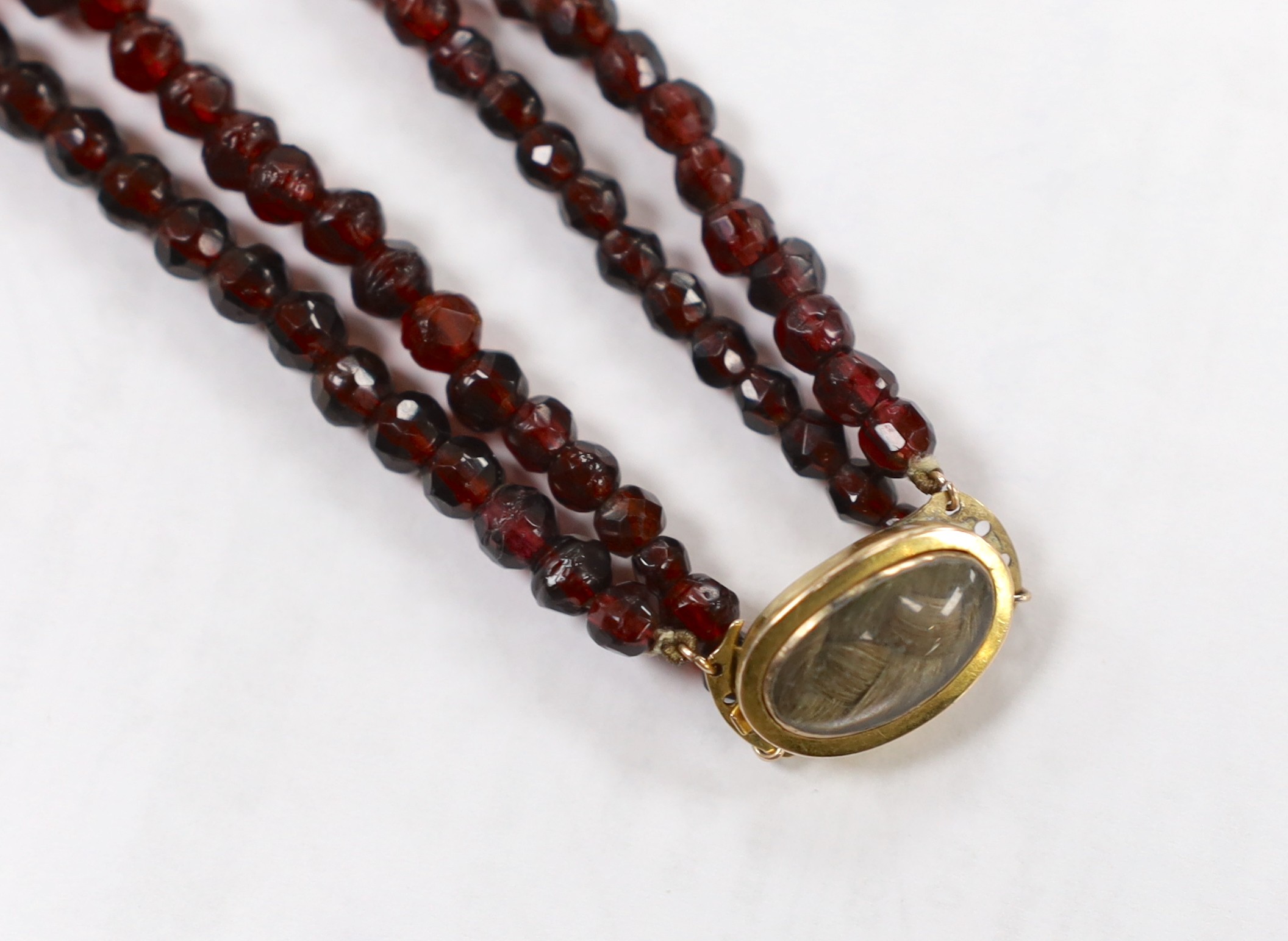 A George III twin strand facetted red paste? necklace, with yellow metal and plaited hair clasp,