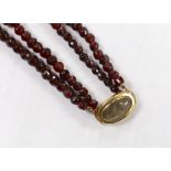 A George III twin strand facetted red paste? necklace, with yellow metal and plaited hair clasp,