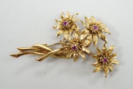 A 1960's 18ct gold and four stone ruby set floral spray brooch, 50mm, gross weight 11.9 grams.