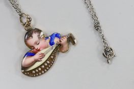 A continental yellow metal and enamel pendant, depicting a child with mandolin, 34mm, on a white