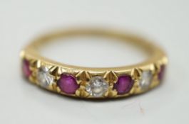 A modern 18ct gold, four stone ruby and three stone diamond set half hoop ring, size L/M, gross