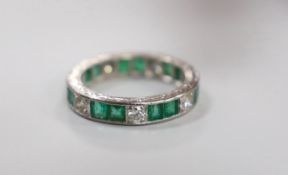 A mid 20th century 18ct white metal, emerald and diamond set full eternity ring(a.f.), size M/N,