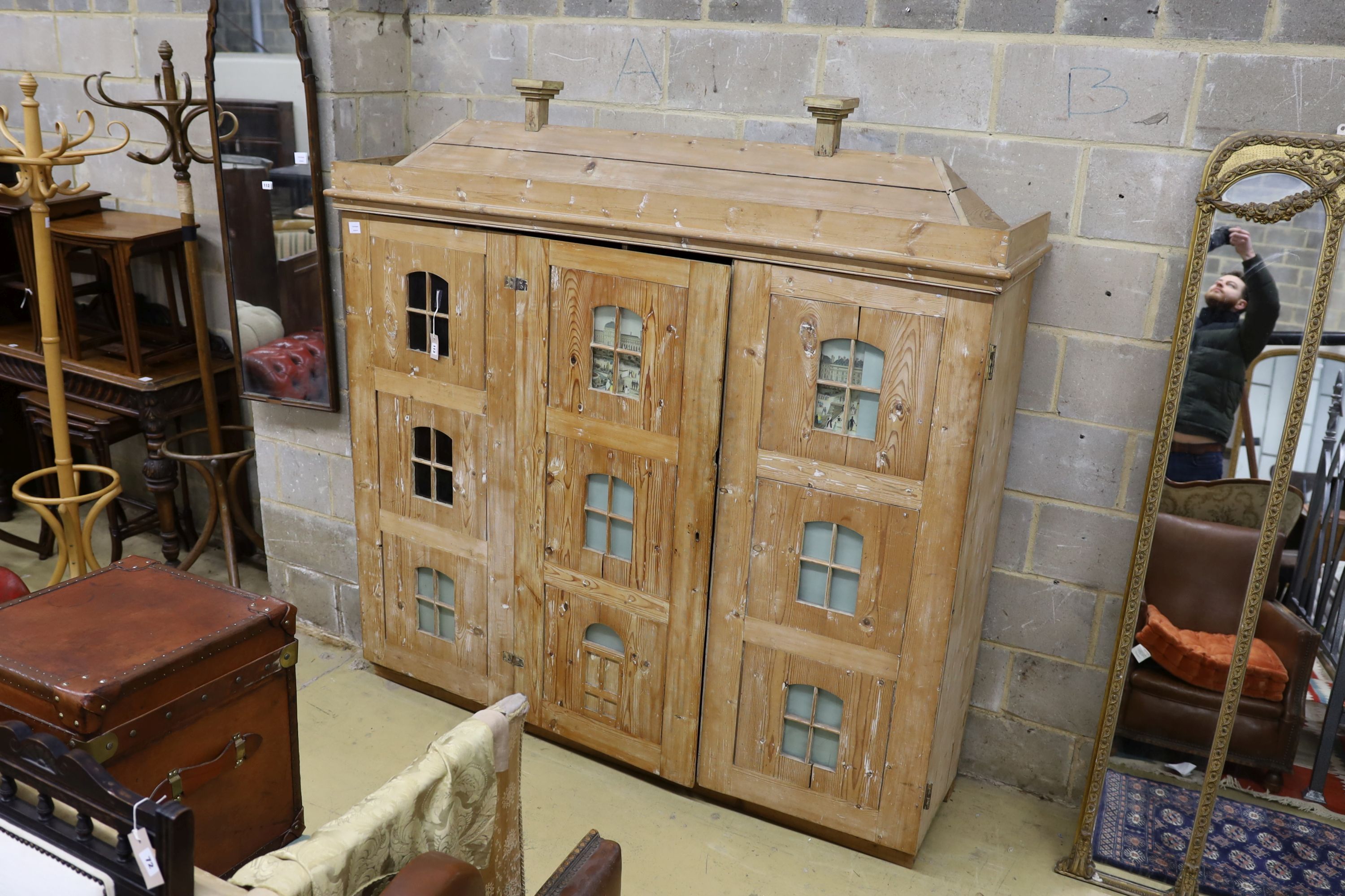 A 19th century stripped pine hall cupboard modelled as a dolls house the two door nine window facade