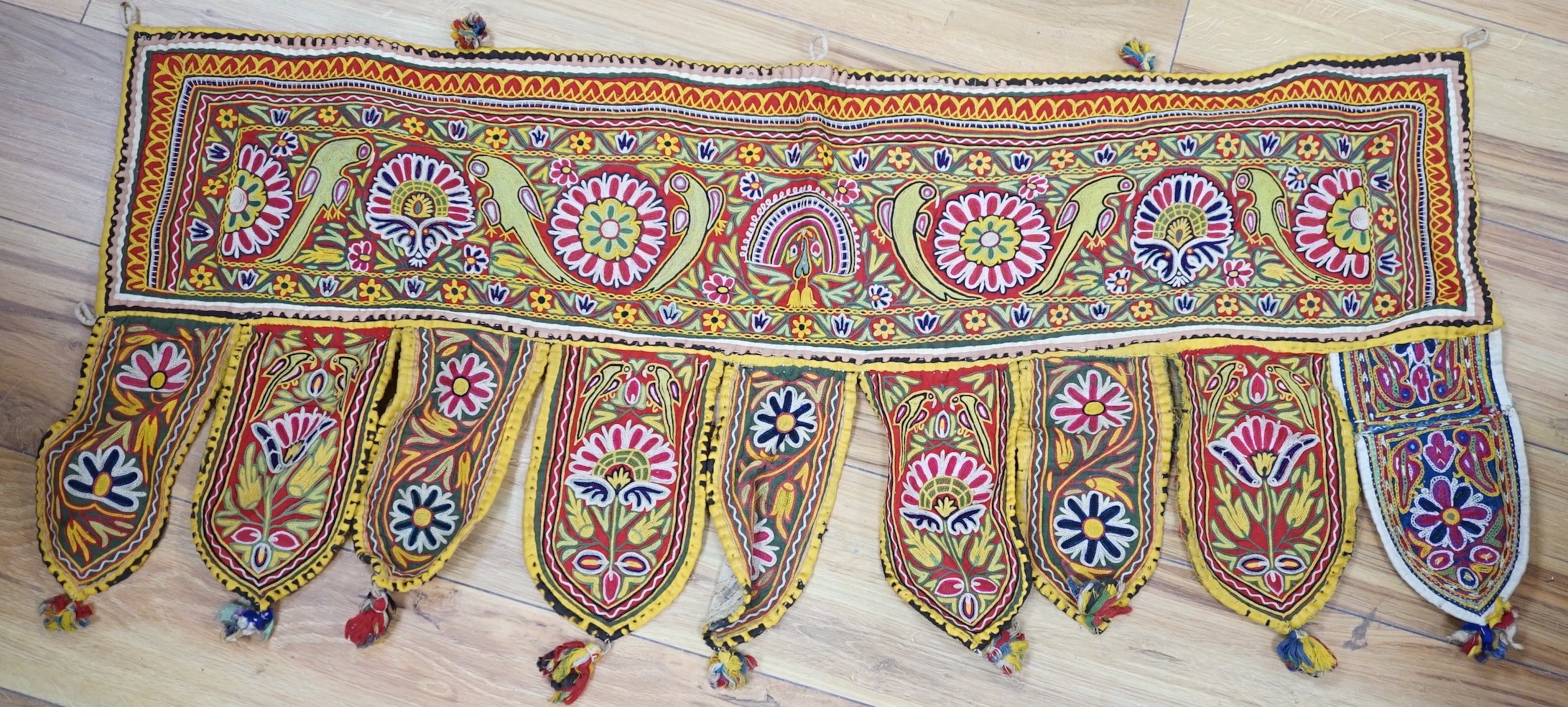 A collection of Indian mirrored worked hangings, a length of batik fabric and a woven shawl,